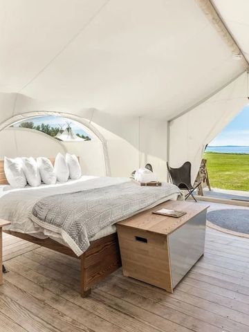 Luxuszelt mit Blick auf grüne Wiese und Meer im Hintergrund