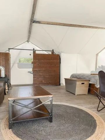 Offenes Zeltinterieur mit Sitzbereich und Bett aus Holz