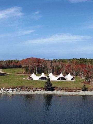 Weiße Zelte in einer grünen Landschaft mit Blick auf das Wasser