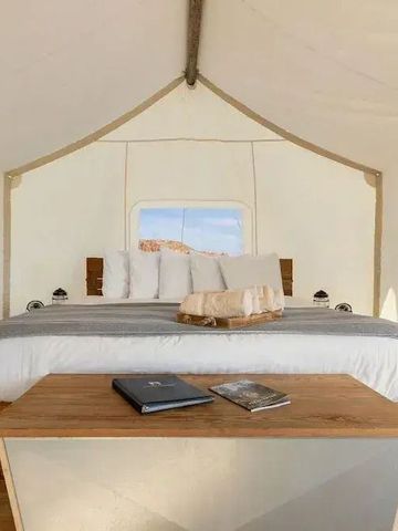 Zeltunterkunft mit Doppelbett, Tisch und Blick auf die Natur. Helles und geräumiges Design.