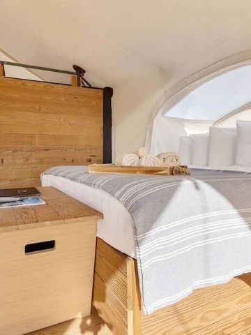 Schlichte Eleganz im Zelt mit modernem Bettgestell und Holzdetails. Warmes Tageslicht.