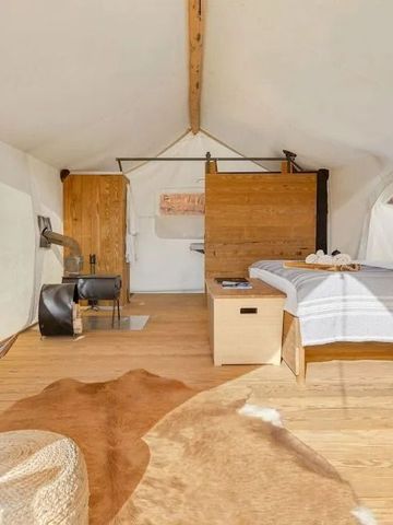 Großzügiges Zelt mit Holzelementen, Sesseln und markanter Holztrennwand. Rustikaler Chic.