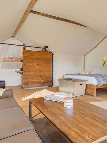 Zeltinnenraum mit Sofa und Holztisch. Entspanntes Wohnambiente und viel Platz.