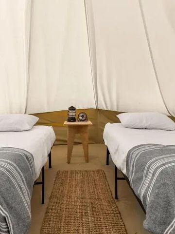 Zelt mit zwei Einzelbetten. Dezente Dekoration und weiche Bettwäsche.