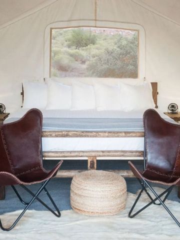 Zelt mit Doppelbett und Ledersesseln in einem naturnahen Hotel.