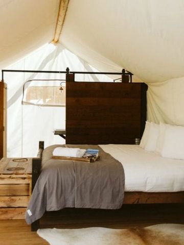 Gemütliches Zelt mit Bett und rustikalen Holzmöbeln in einem Hotel.