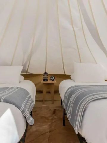 Zeltinnere mit zwei Einzelbetten und minimalistischer Einrichtung.