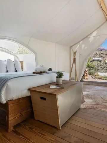 Zelt mit luxuriösem Bett und Blick auf die umliegende Landschaft.