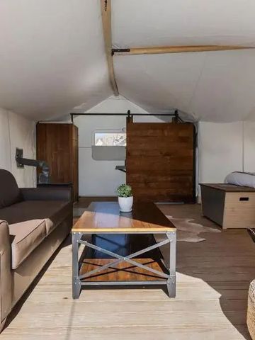 Wohnbereich eines Zeltes mit Sofa und Bett in rustikalem Stil.