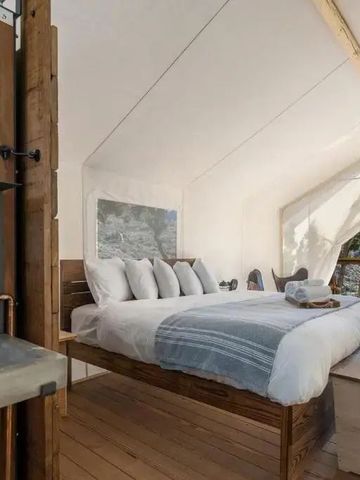 Luxuriöser Zelt-Innenraum mit Doppelbett und Waschbecken, Blick ins Freie