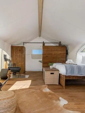 Helles Zelt mit Doppelbett, Holztrennwand und Sitzgelegenheiten