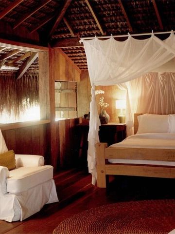 Charmantes Zimmer mit Himmelbett unter einem rustikalen Strohdach