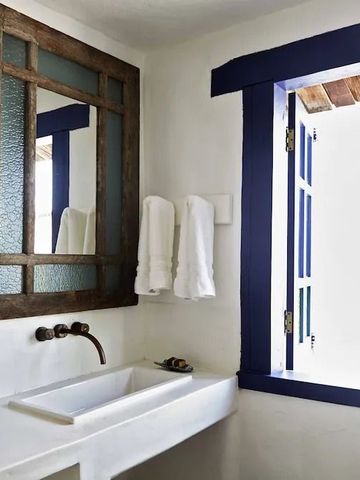 Schlichtes Badezimmer mit hölzernem Spiegel und weißem Waschbecken