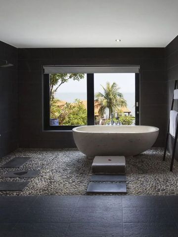 Luxuriöses Badezimmer mit freistehender Badewanne und Blick auf den Garten