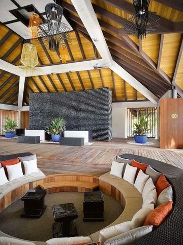 Luxuriöse Hotellobby mit Holzbalkendecke und eleganter Sitzgruppe in der Mitte.