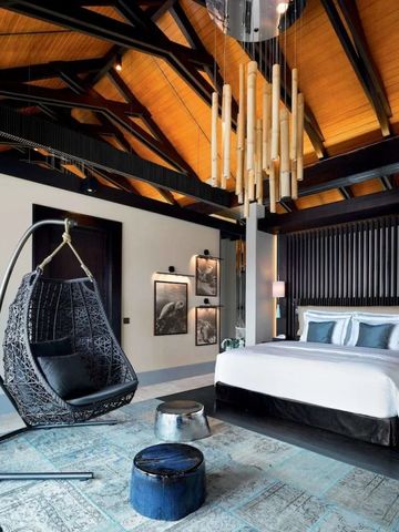 Luxuriöses Schlafzimmer mit Designerleuchte und Hängesessel unter einer hohen Holzdecke.