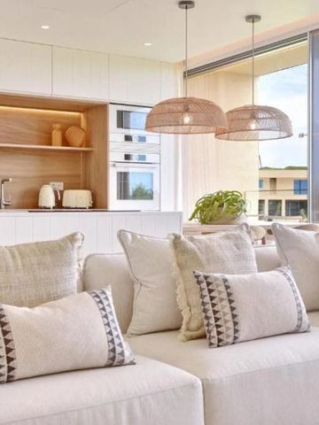 Gemütlicher Wohnbereich mit hellen Kissen und moderner Küche im Hintergrund