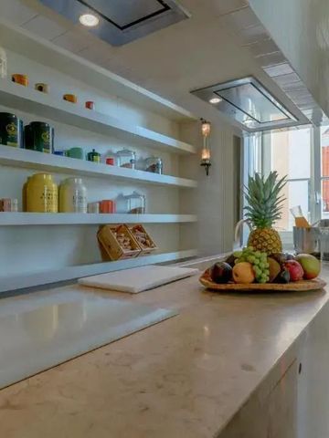 Geräumige Hotelküche mit offener Ablage und Obstteller auf der Arbeitsplatte.