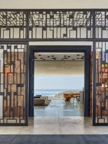Modern gestalteter Eingang mit geometrischen Metallmustern und Blick aufs Meer