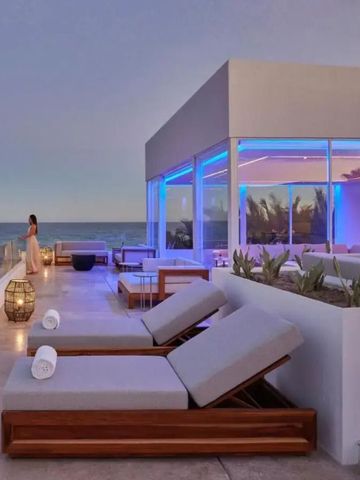 Dachterrasse mit Liegen und modernem Glasgebäude bei Sonnenuntergang