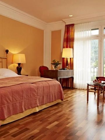 Elegant eingerichtetes Hotelzimmer mit großem Bett und Holzfußboden