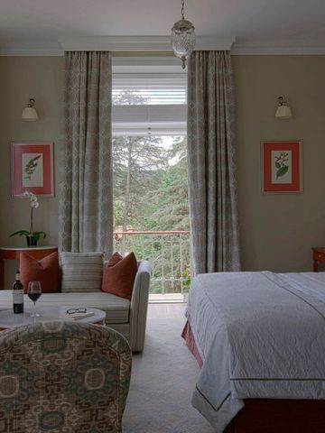 Elegantes Hotelzimmer mit großen Fenstern und Blick auf grüne Bäume