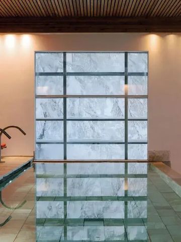 Moderner Innenpool mit eleganter Marmorwand und Lichtern.