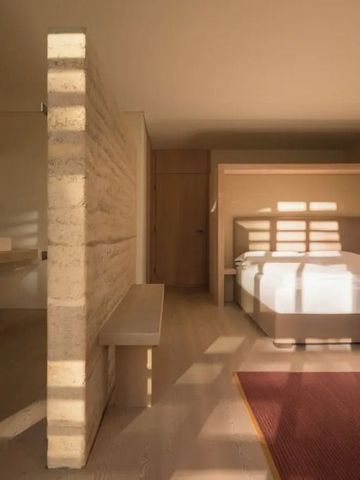 Helles Zimmer mit großem Bett und Sonnenlicht durch Fenster.