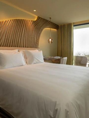 Geräumiges Hotelzimmer mit großem Bett und Blick auf den Balkon