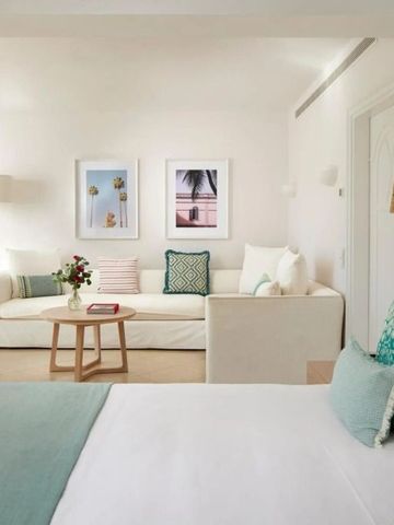 Luxuriöses Schlafzimmer mit angrenzender Sitzecke und pastellfarbenem Dekor.