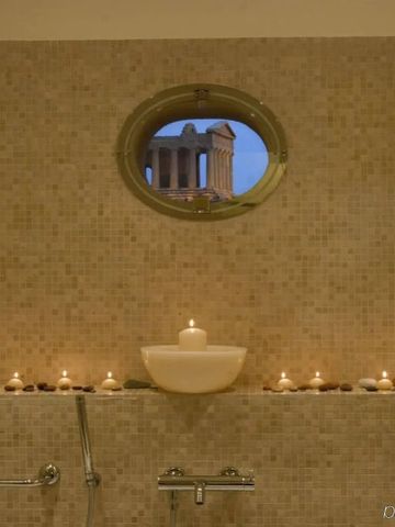 Stimmungsvolles Badezimmer mit Kerzen und Rundfenster zum Tempel