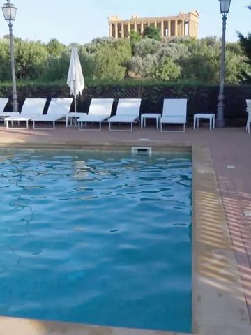 Blick auf den Pool des Villa Athena Resort mit antikem Tempel im Hintergrund