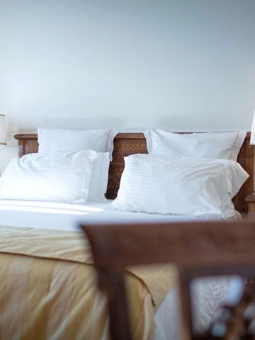 Luxuriöses Schlafzimmer mit Doppelbett, weißen Kissen und Nachttischlampen