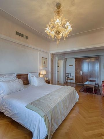 Geräumiges Hotelzimmer mit Doppelbett, Leuchter und Holzboden