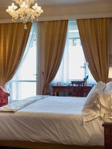 Elegantes Schlafzimmer mit Kronleuchter und großen Fenstern im Villa Cortine Palace Hotel
