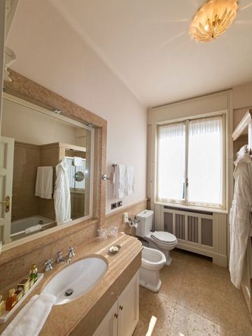 Helles Badezimmer mit großer Spiegelfront und klassischem Design im Hotel