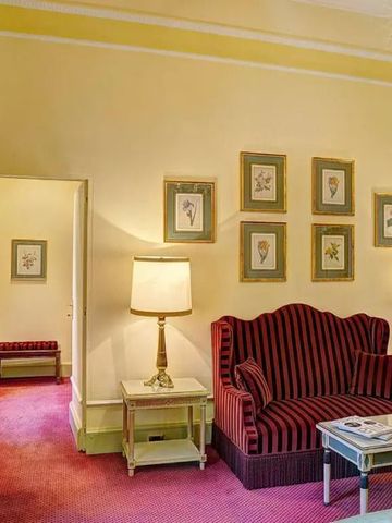 Elegantes Wohnzimmer in einer Suite mit roten Möbeln und klassischen Kunstwerken