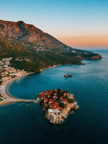 Luftaufnahme einer Küste mit einem malerischen Inselstädtchen bei Sonnenuntergang.