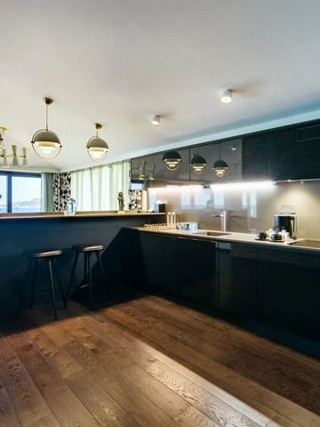 Moderne Küche in einer Suite mit Holzboden und Barhockern. Blick auf das Meer.