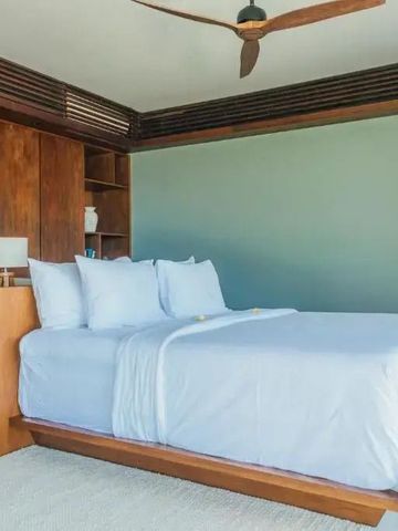 Modernes Schlafzimmer mit großem Bett und Holzverkleidung im tropischen Stil