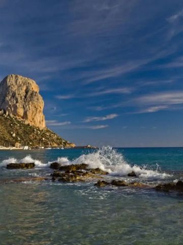 Dramatische Felsformation am Meer mit Wellengang und blauem Himmel