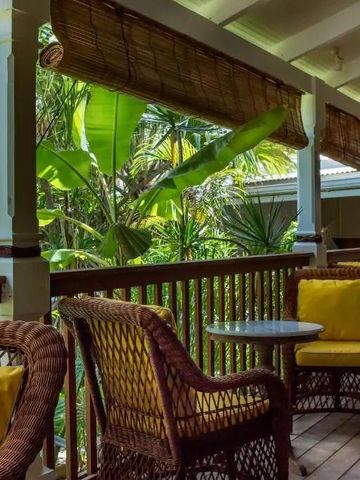 Gemütliche Veranda mit Korbmöbeln und Blick ins Grüne