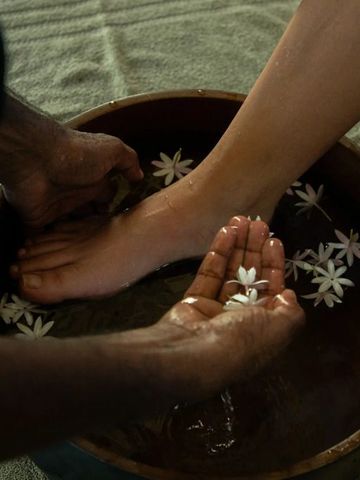 Wellnessfußbad mit Blumen in einer Holzschale