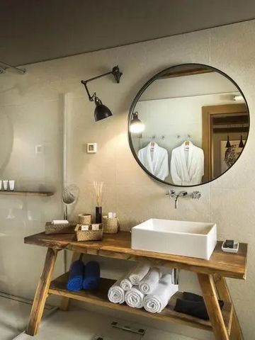 Stilvolles Badezimmer mit rundem Spiegel und Holzmöbeln