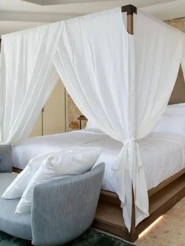 Himmelbett mit weißen Vorhängen in einem luxuriösen Hotelzimmer