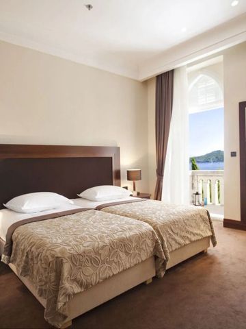 Elegantes Hotelzimmer mit Doppelbett, hellem Dekor und Balkon mit Meerblick