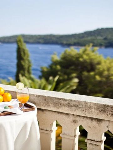 Blick von der Terrasse mit Tisch, Obst und Saft auf das Meer und grüne Landschaft