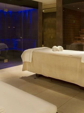 Entspannungsraum mit Massageliegen und glasabgetrenntem Raum