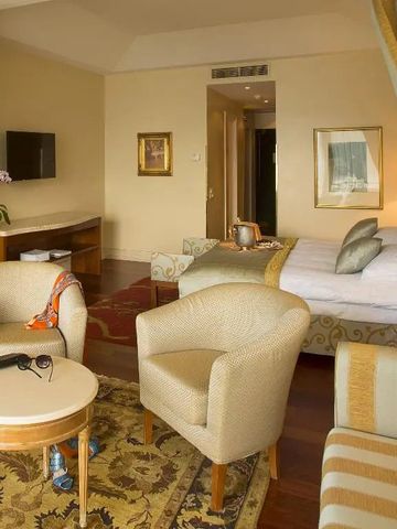 Elegantes Hotelzimmer mit Sitzecke und Doppelbett in warmen Tönen