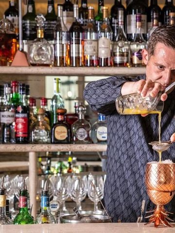 Barkeeper beim Mixen eines Cocktails in einer gut bestückten Bar